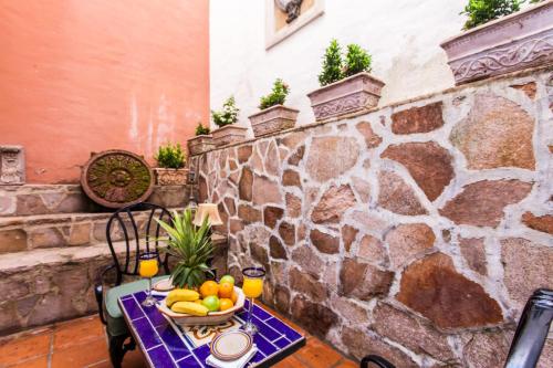 a table with a bowl of fruit on a stone wall at Garlands Del Rio Riverside Boutique Hotel in Puerto Vallarta