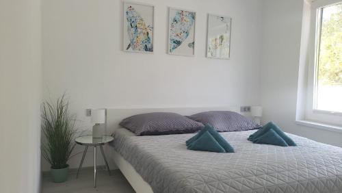 Dormitorio blanco con cama con almohadas azules en Prázdninový dům u moře, en Bilice