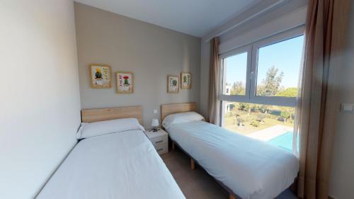 two beds in a room with a window at Souvenir by ON Travel in Oliva