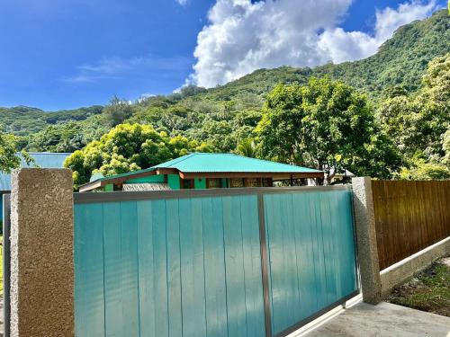 a blue fence with a house behind it at Faré blue lagoon in Moorea