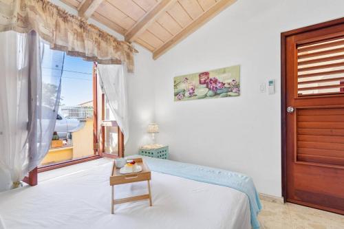 um quarto com uma cama, uma janela e uma mesa em Villa Laurence Aruban Oasis Footsteps To Ocean em Savaneta