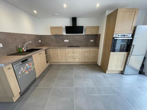 une cuisine avec des armoires en bois et un réfrigérateur blanc dans l'établissement Wissant Villa Sainte Thérèse, à Wissant