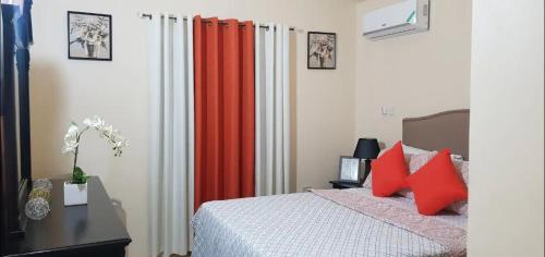 a bedroom with an orange curtain and a bed at Gems Pool Side Chillax Stay in Portmore