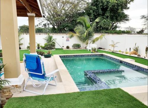 um quintal com uma piscina e uma cadeira azul em Gems Pool Side Chillax Stay em Portmore