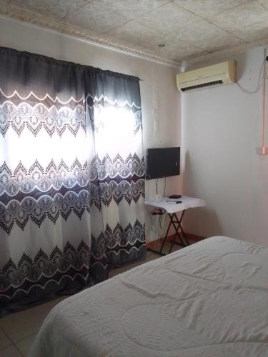 1 dormitorio con cama, ventana y escritorio en Maun self catering accommodation, en Maun