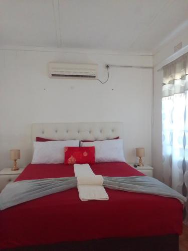 a bedroom with a red bed with two towels on it at Maun self catering accommodation in Maun
