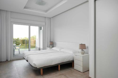 Un dormitorio blanco con dos camas y una ventana. en Leafy by ON Travel, en Oliva