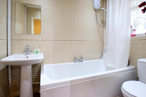 uma casa de banho com um lavatório, uma banheira e um WC. em 3 bedrooms Sleeps 8 Self Catering House Near California Cliffs and Great Yarmouth Beach,Norfolk em Norwich