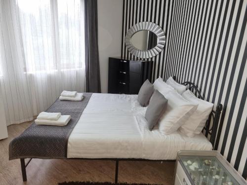 a bedroom with a bed with white sheets and a mirror at Apartament BEACH VIBES Nessebar in Nesebar