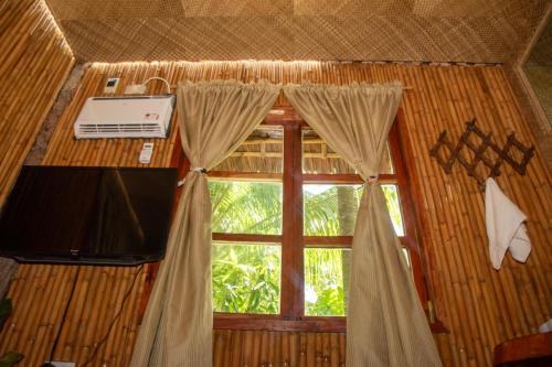 een kamer met een raam met gordijnen en een televisie bij Dumaguete Oasis Treehouse in Dumaguete