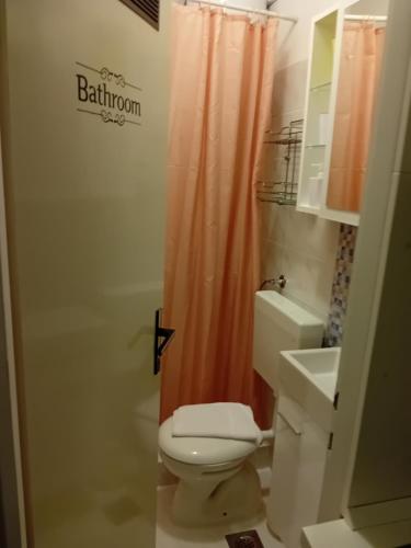 La salle de bains est pourvue d'un rideau de douche orange et de toilettes. dans l'établissement Studio Sofia 2, à Novalja