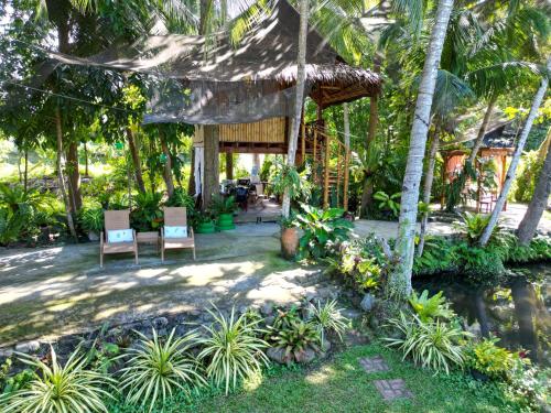 une terrasse avec 2 chaises et une maison avec des palmiers dans l'établissement Dumaguete Oasis Treehouse, à Dumaguete