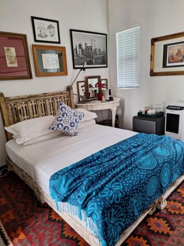 a bedroom with a large bed with a blue blanket at Acacia Home in Graaff-Reinet