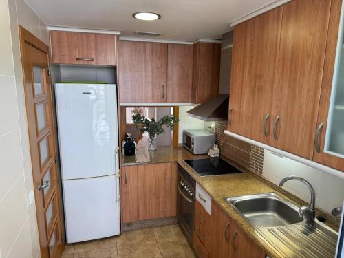 デニアにあるResidencial Aquamarinasのキッチン(木製キャビネット、白い冷蔵庫付)