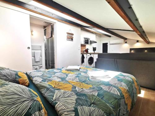une chambre avec un grand lit avec une couverture colorée dans l'établissement Le Tropical l Calme l Clim l Parking gratuit, à Istres