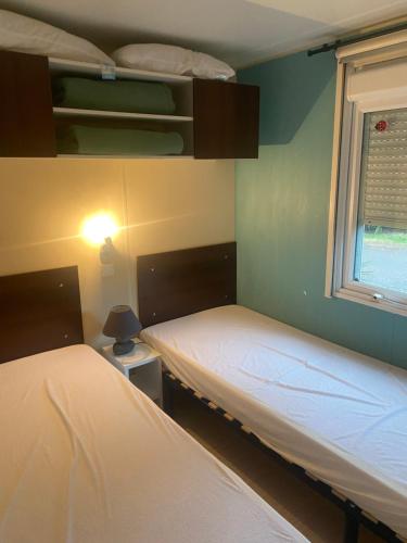 two beds in a room with a window at Mobilhome in Azur