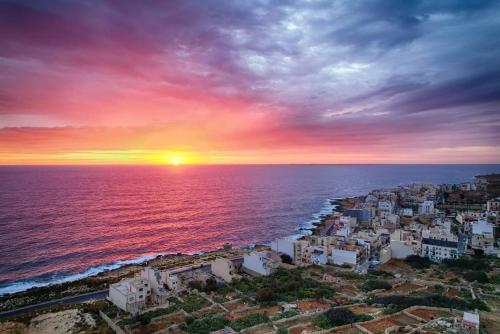 een luchtzicht op een strand met een zonsondergang bij Star Dream Apartment in Xgħajra