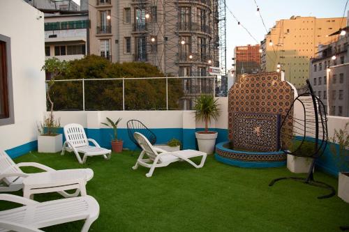 un patio en la azotea con sillas blancas y césped verde en Callao Luxury Hostel en Buenos Aires