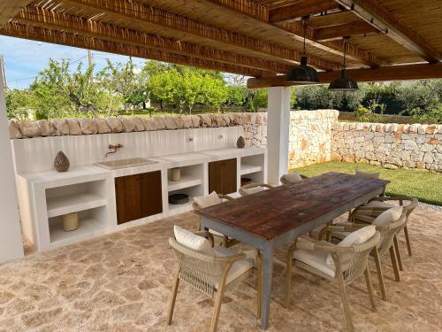 Una cocina al aire libre con una mesa y sillas de madera. en Trullo Gemma, en Martina Franca