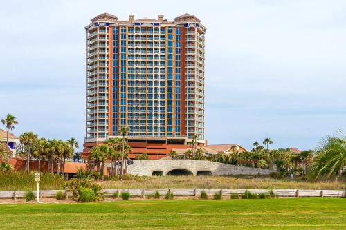 a tall building in front of a green field at Pensacola Beach Penthouse with View and Pool Access! in Pensacola Beach