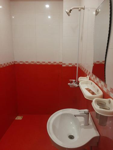 Baño rojo con aseo y lavamanos en Madina Hotel, en Faisalabad
