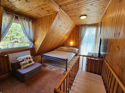 Zimmer mit einem Bett und einem Stuhl in einer Hütte in der Unterkunft Ferienhaus "BASTEK1" am See mit Kamin & WLAN - Domek Letniskowy BASTEK in Pasym