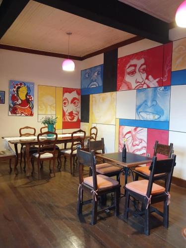 um restaurante com mesas e cadeiras e pinturas na parede em Brumas Ouro Preto Hostel e Pousada em Ouro Preto