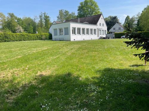 een grote tuin met een wit huis met een groot gazon bij Villa direkt am Baldeneysee in Essen