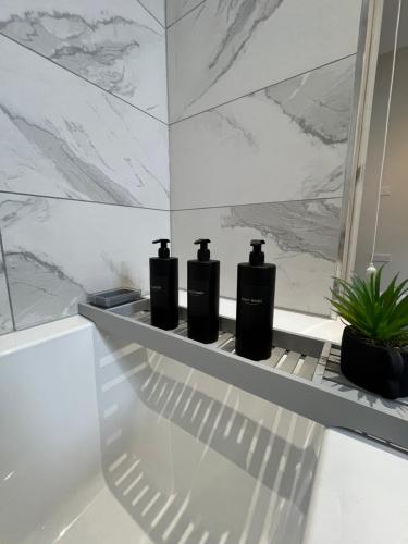 巴恩斯利的住宿－The perfect place，浴室的架子上装有三瓶黑瓶