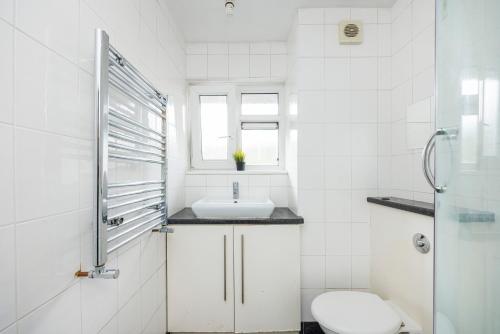 a white bathroom with a sink and a toilet at Trendy four bed flat in islington in London