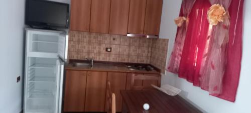 cocina pequeña con armarios de madera y TV en Aral guesthouse, en Borsh