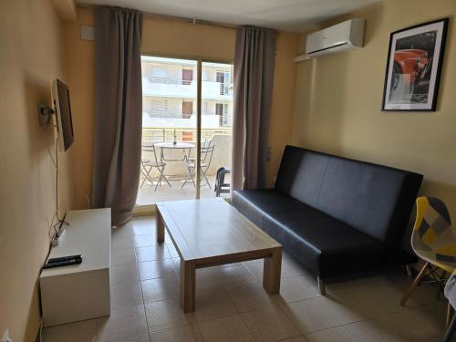 ein Wohnzimmer mit einem schwarzen Sofa und einem Tisch in der Unterkunft Sea ​​apartments in La Pineda