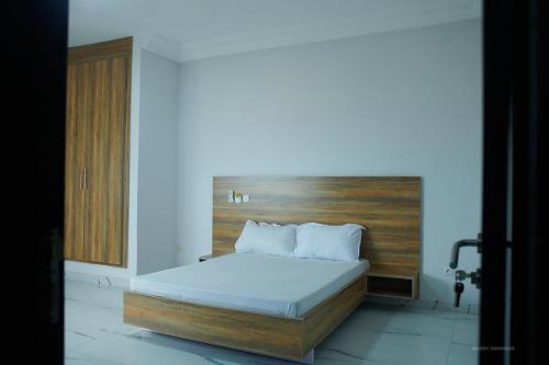 a bedroom with a bed with a wooden headboard at Le VÏU2 in Cotonou