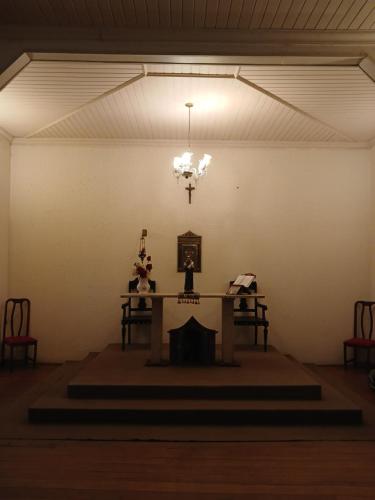 Habitación con mesa y lámpara de araña. en Brumas Ouro Preto Hostel e Pousada, en Ouro Preto