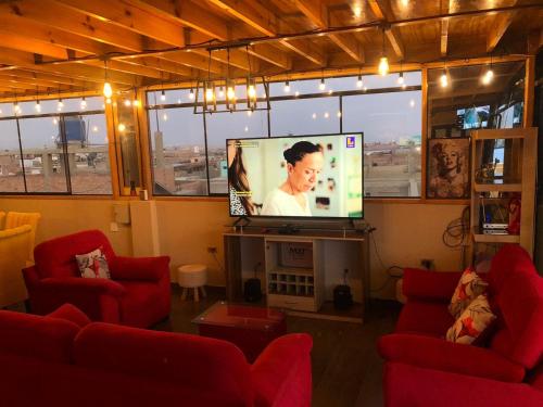 ein Wohnzimmer mit 2 roten Stühlen und einem Flachbild-TV in der Unterkunft Big blue house in Chimbote