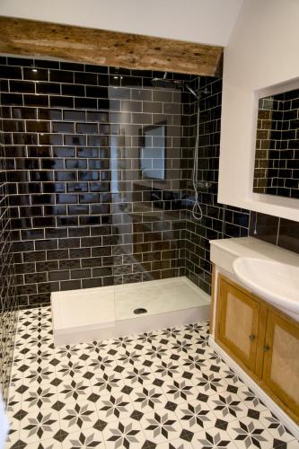 a bathroom with a shower and a sink and black tiles at The Beeches - Chatsworth Apartment No 5 - Sleeps 4 in Baslow