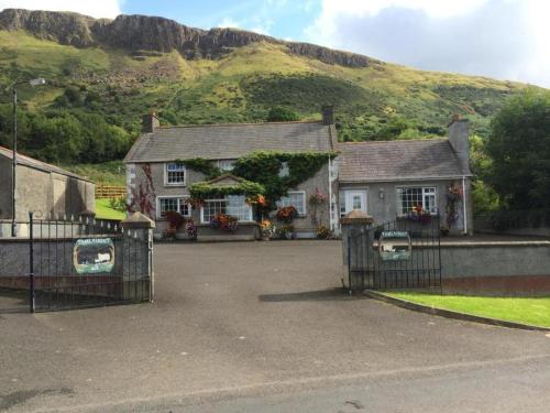 a house with a gate and a mountain in the background at Tamlaught house in Glenariff