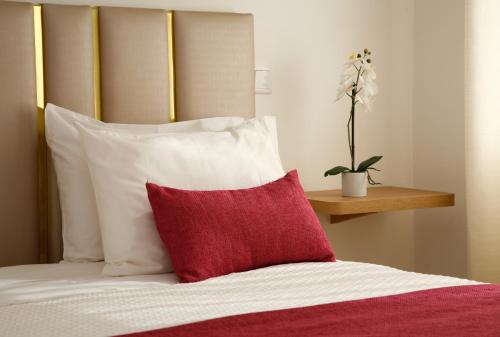 a bed with white pillows and a red pillow at Nova Delpa AL in Caldas da Rainha
