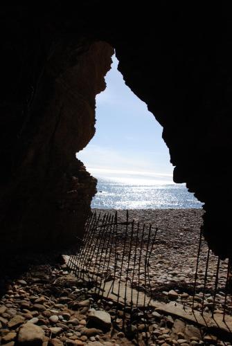 a cave on a beach with the ocean in the background at Faodail 'a lucky find' in Dunbeath