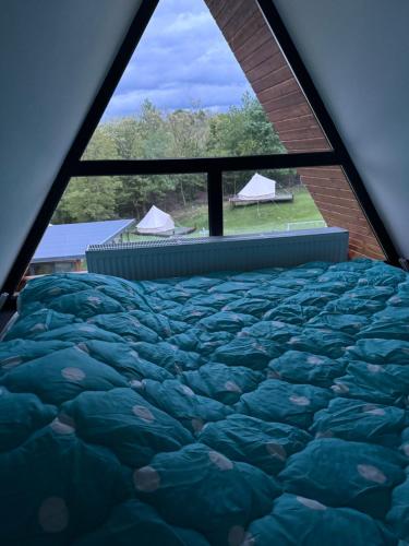 a bed in a room with a large window at STORY GLAMPING POLOVRAGI in Racoviţa