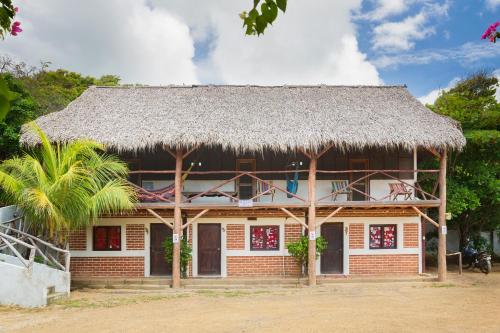 um edifício com um telhado de palha e uma palmeira em Finca Popoyo em Popoyo