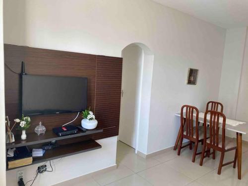 un salon avec une table, deux chaises et une télévision dans l'établissement Apartamento perto de tudo em condomínio fechado., à Salvador
