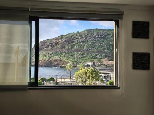 ventana con vistas al océano y a la montaña en VIP Paradise Apartment, en Machico