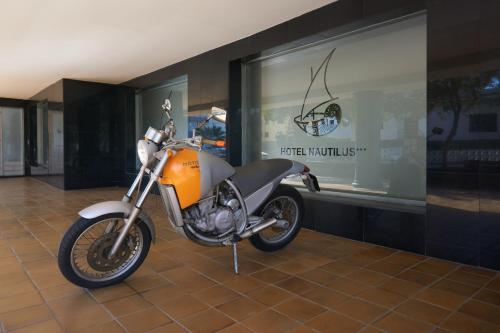 an orange motorcycle parked in front of a window at Nautilus Hotel in Roses