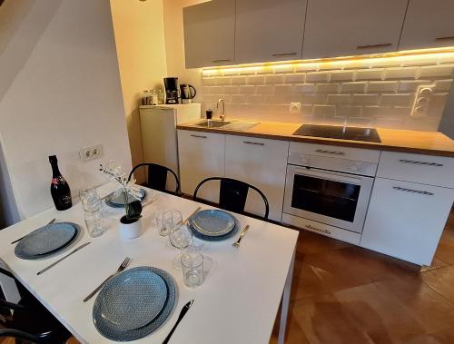 une cuisine avec une table avec des assiettes et des verres dessus dans l'établissement La Garriguette Appart centre historique calme climatisé 6 à 8 couchages, à Arles