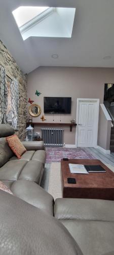 ein Wohnzimmer mit einem Sofa und einem Tisch in der Unterkunft Cobbles cottage - 2 bedroom stone built cottage in Ballynahinch