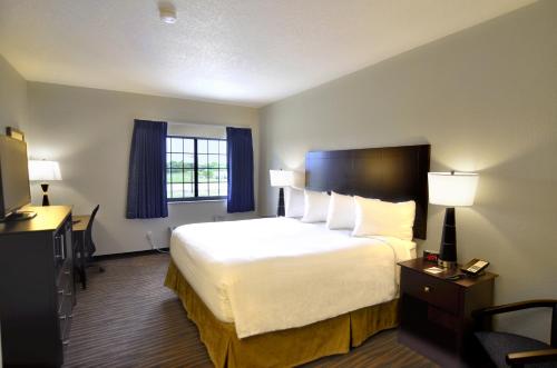 a hotel room with a large bed and a desk at Cobblestone Inn & Suites - Holstein in Holstein