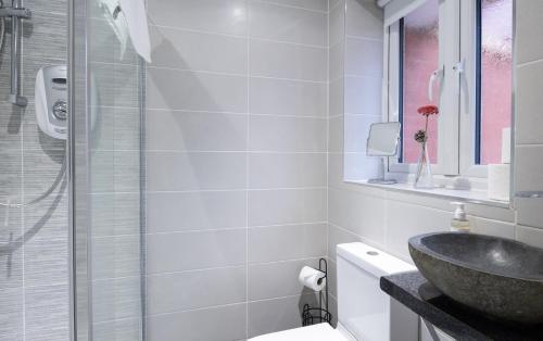 La salle de bains est pourvue d'un lavabo et d'une douche en verre. dans l'établissement Cambridge Fennec 4-BR Detached House, Sleeps 6, à Cambridge