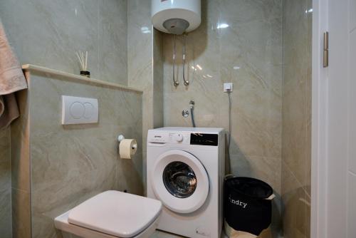 a bathroom with a toilet and a washing machine at TriA Studio in Bar