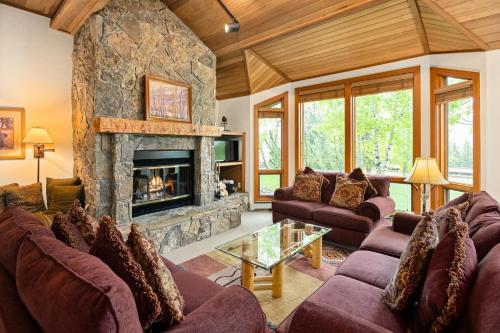 una sala de estar con sofás y una chimenea de piedra. en Lovely Townhome with Snowmass View and Ski-In Ski-Out townhouse, en Snowmass Village